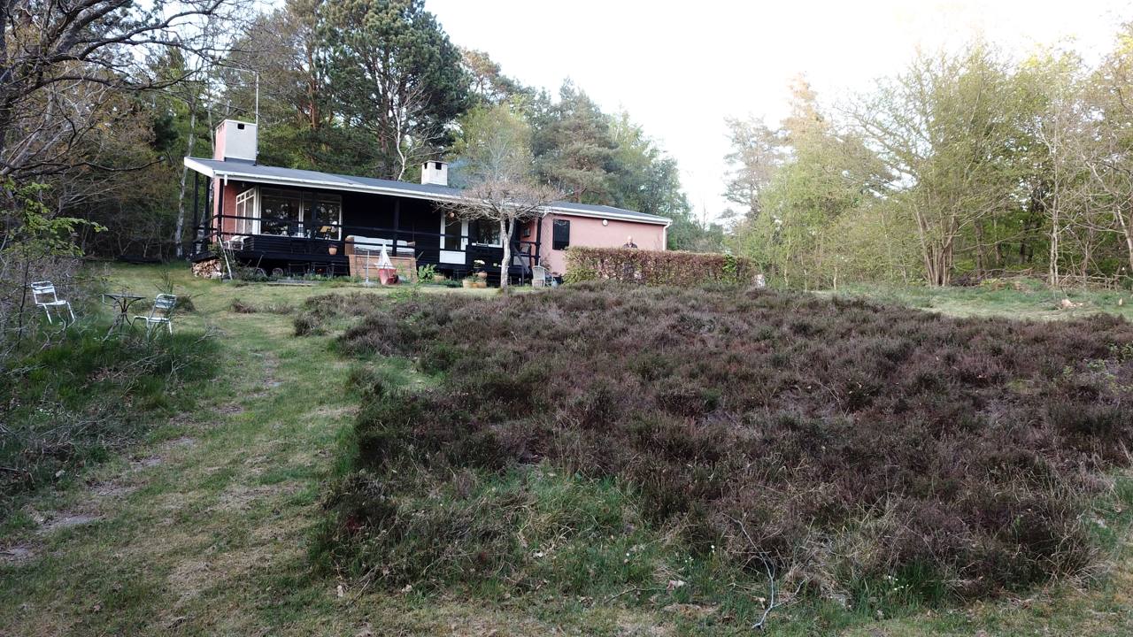 Sommerhus set fra haven med terrasse, hede og skov ved Lyngsbæk Strand i Ebeltoft
